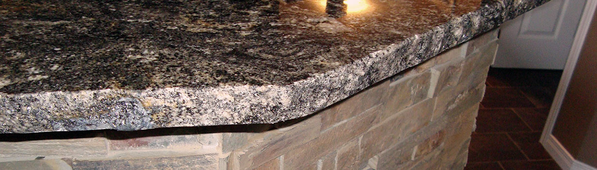 Close up of a dark granite kitchen counter top and stone veneer under it.
